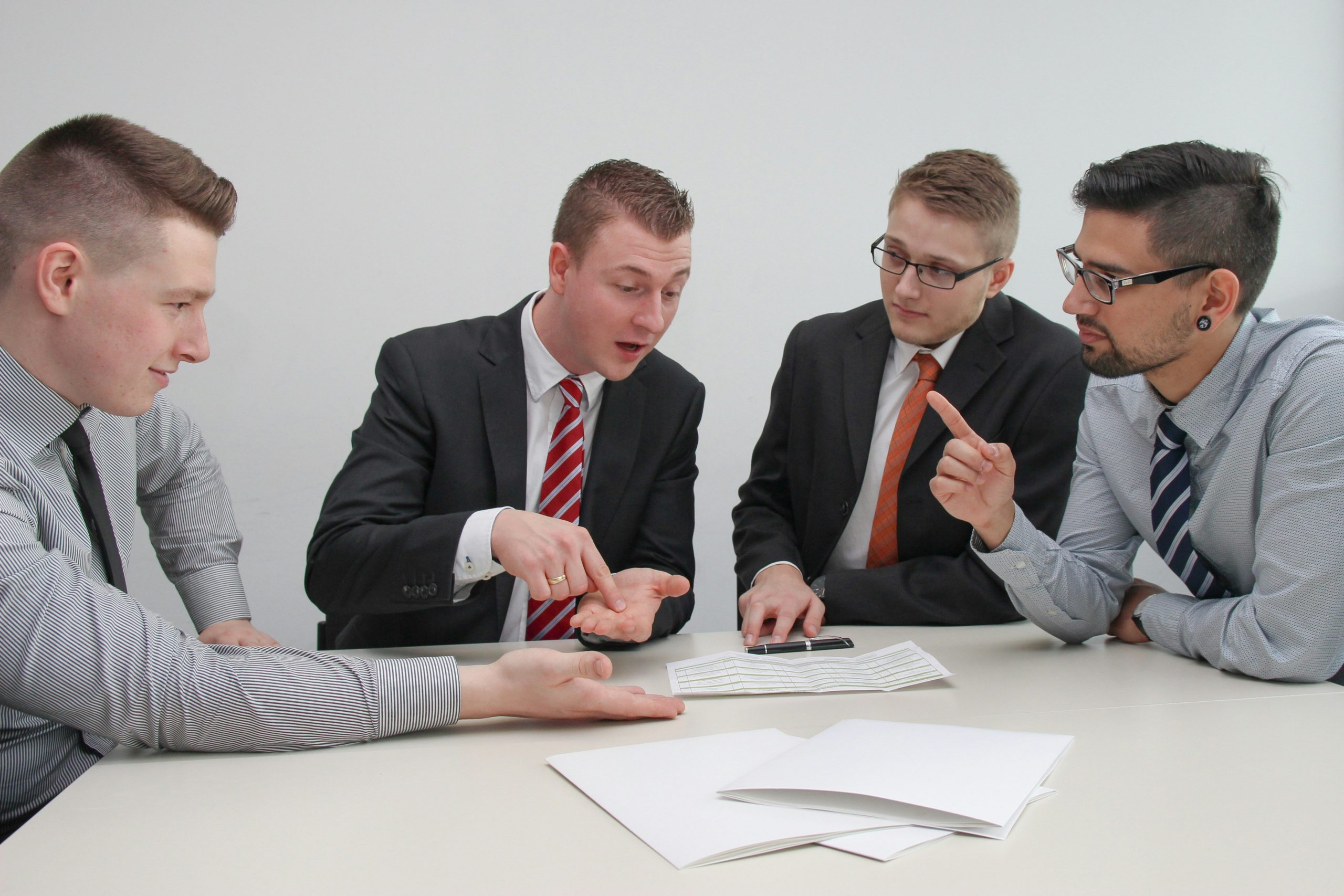 Man looking confused at tax forms surrounded by calculators and coffee mugs.