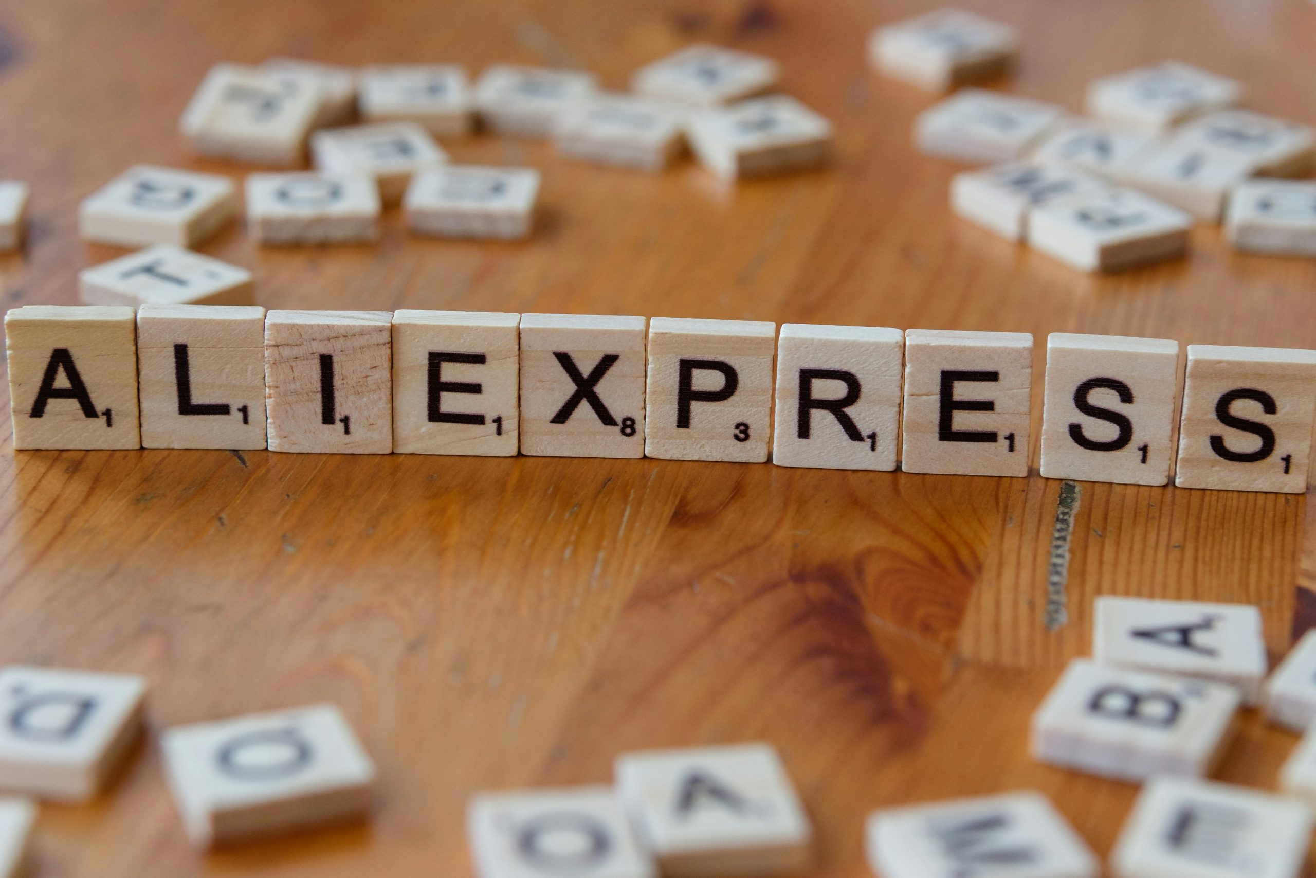 A wooden block spelling the word allexpress on a table
